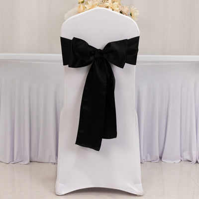 White chair cover with a large black bow, ideal for events and weddings.