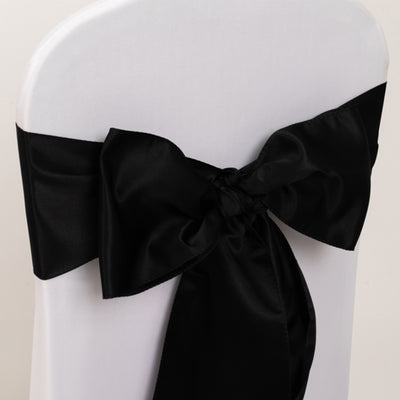 Black satin chair sash bow tied on a white chair.
