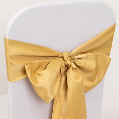 Gold satin chair sash tied in a bow on a white chair.