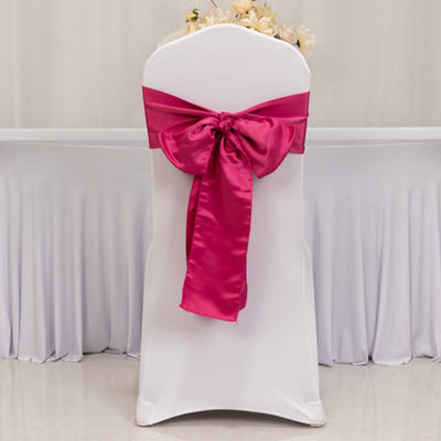 White chair cover with fuchsia satin bow, ideal for events and weddings.