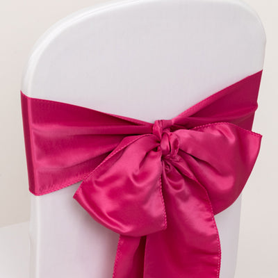 Fuchsia satin chair sash tied in a bow on a white chair.