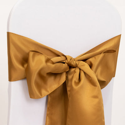 Gold satin chair sash tied in a bow on a white chair.