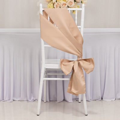 Beige satin chair sash with bow, elegantly draped on a white chair.