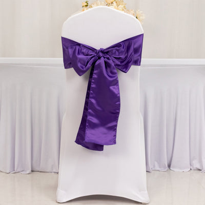 Purple satin chair sash tied on a white chair.