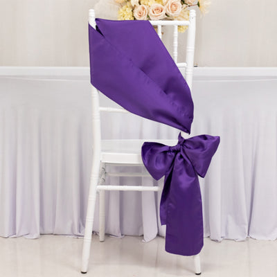 Purple satin chair sash elegantly tied in a bow on a white chair.