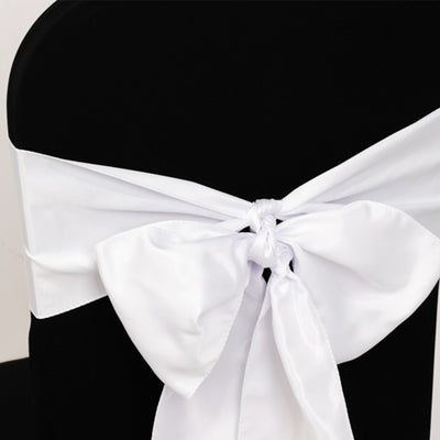 White satin chair sash tied in a bow on a black chair.