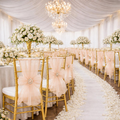 Elegant wedding reception with gold chairs, white roses, and chandelier decor