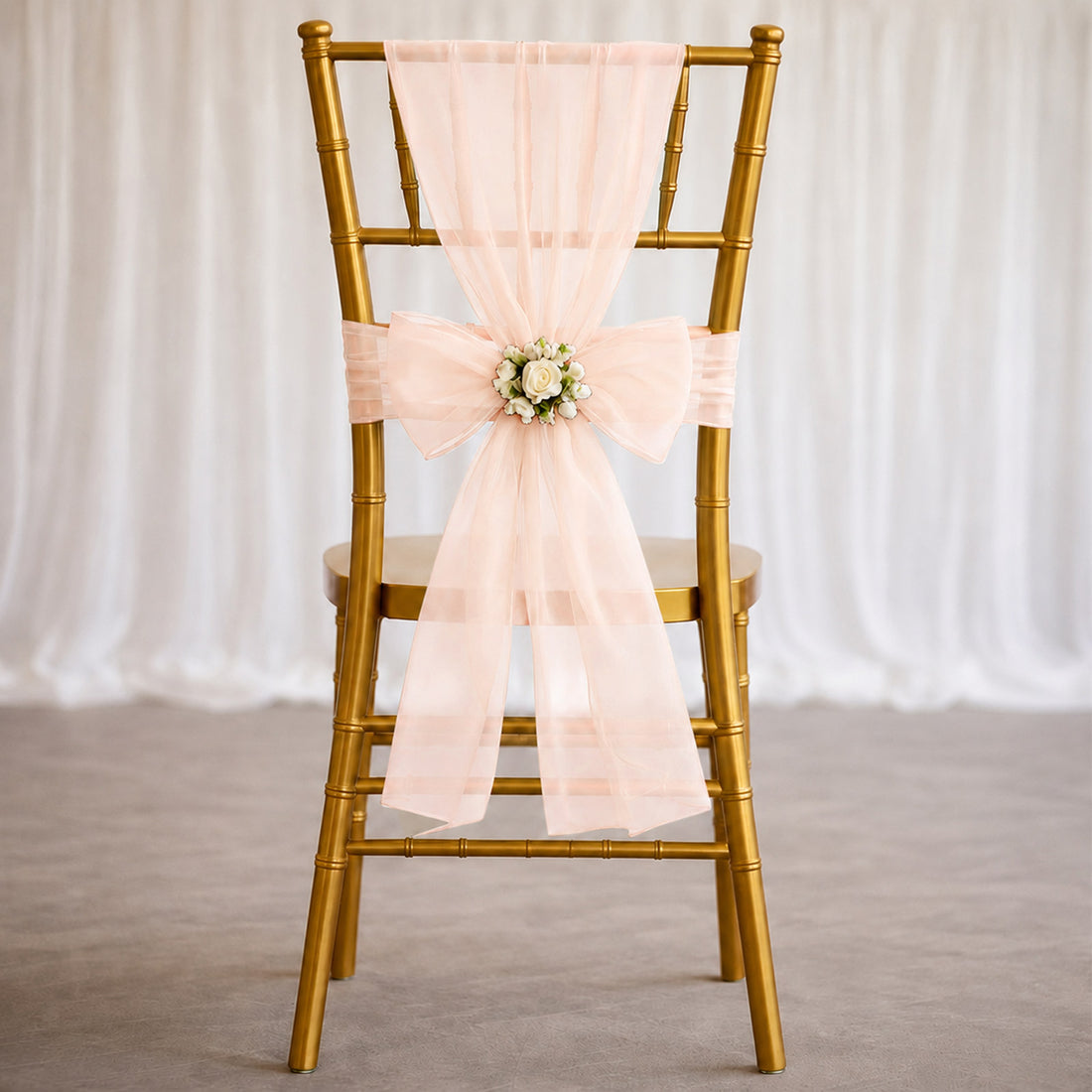 Gold Chiavari chair with blush pink wedding sash and floral centerpiece