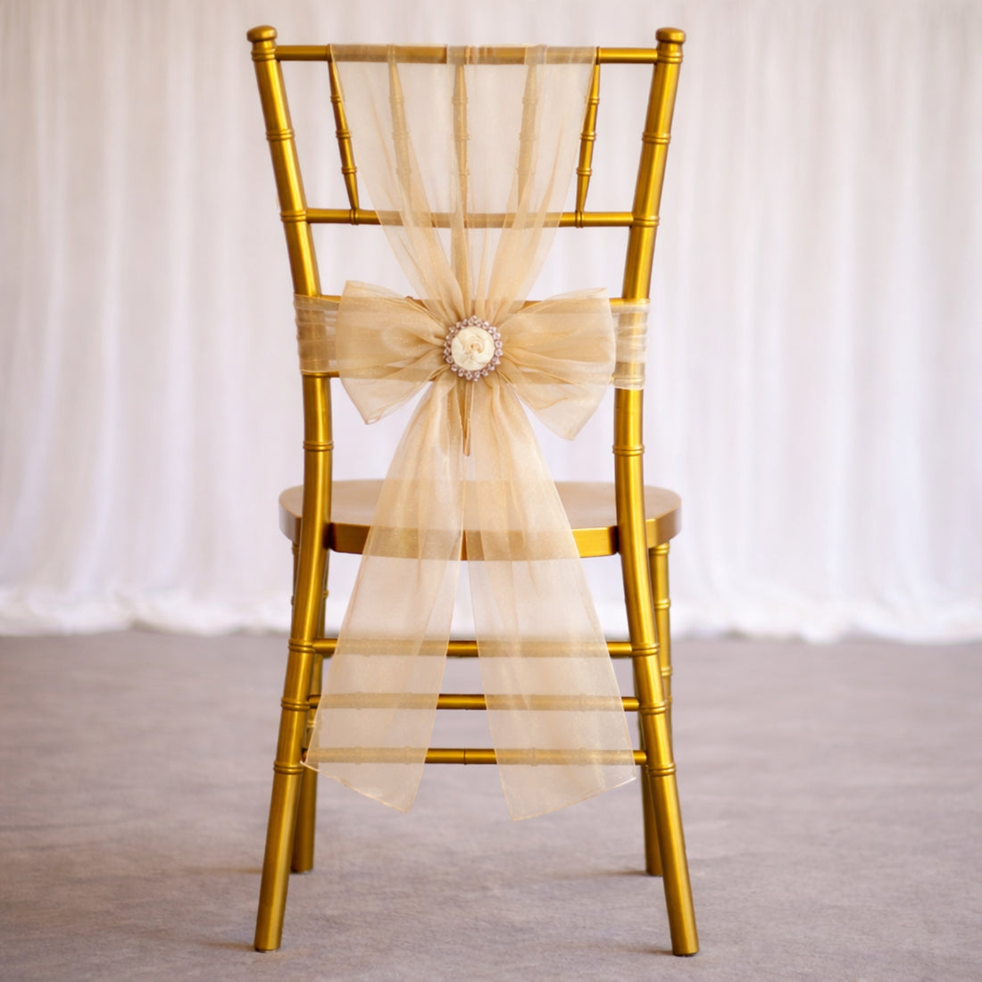 Gold chiavari chair with a beige ribbon bow, elegant event decor.