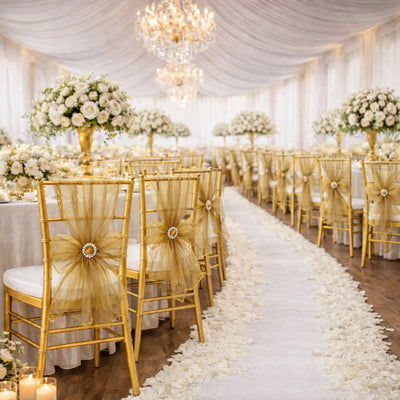 Elegant wedding reception with floral arrangements and gold chairs adorned with bows.