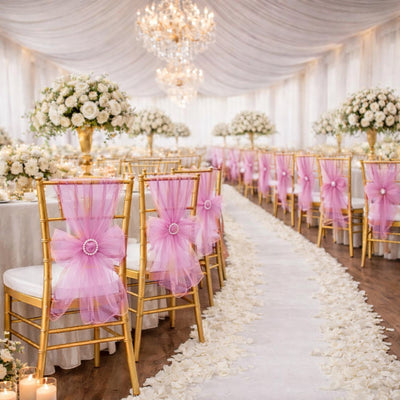 Elegant wedding reception setup with gold chairs and pink decorations.