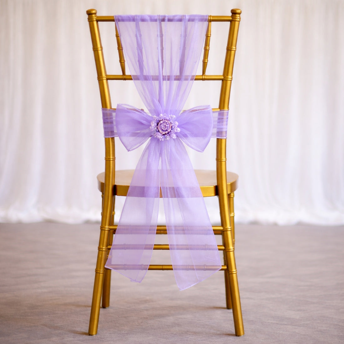 Gold chair with a purple tulle bow and floral accent.