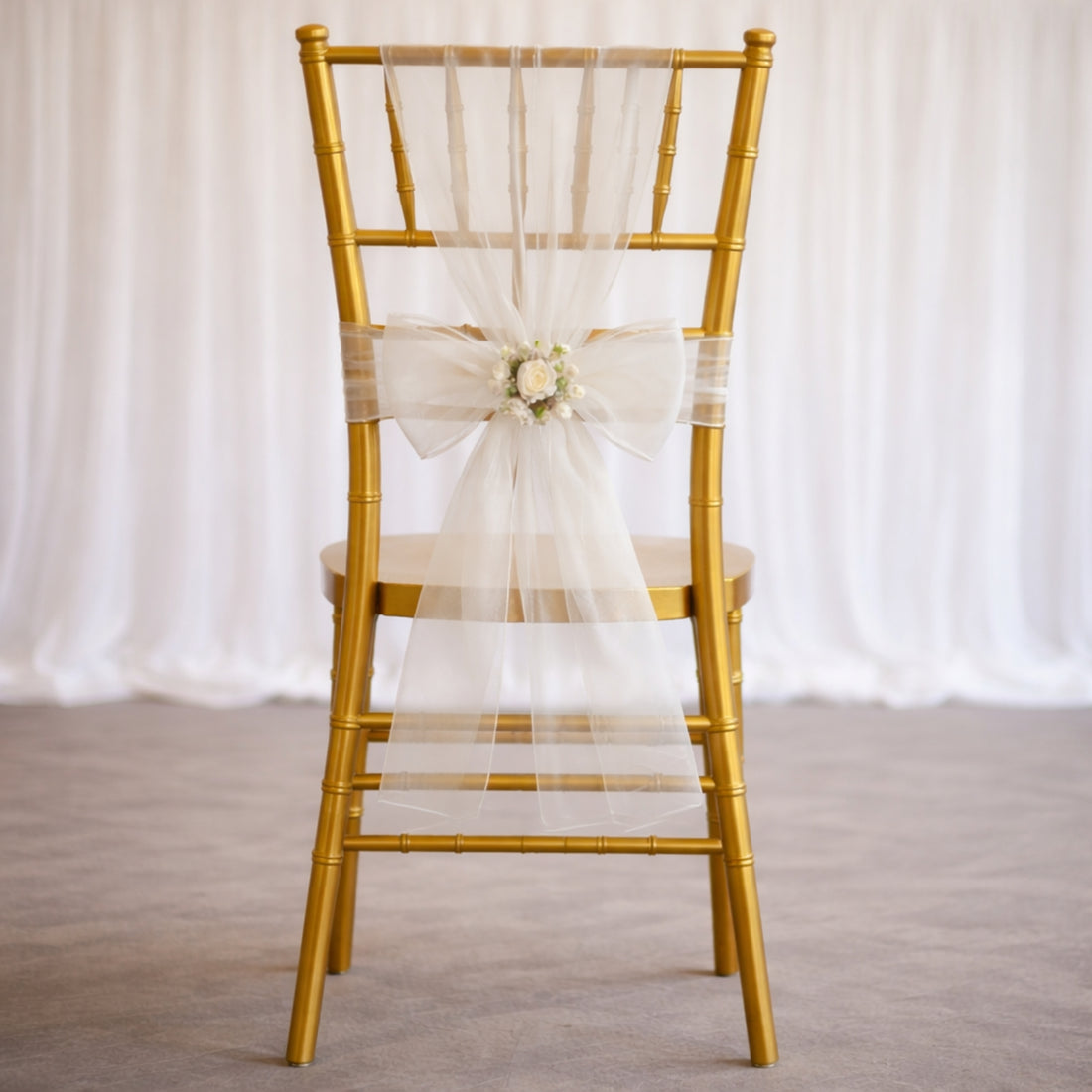 Gold chiavari chair with white tulle and floral bow decoration.