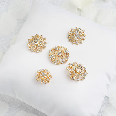 Gold decorative brooches displayed on a white cushion
