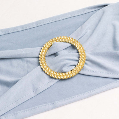 Gold beaded circle brooch on light blue fabric