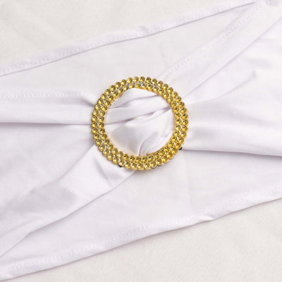 Gold rhinestone-embellished round brooch on white fabric