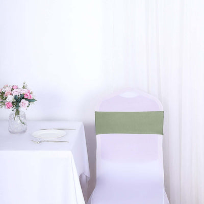 Green chair sash on a white chair beside a table with a vase of flowers.