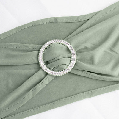 Green fabric with a sparkling circular brooch detail.