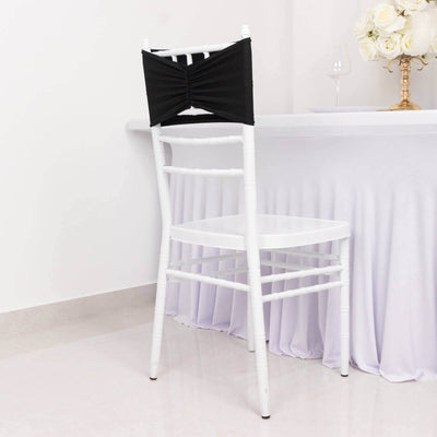 Black chair cover on a white chiavari chair in a decorated setting.
