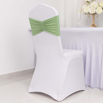 White chair cover with green ruched bow, styled for event decoration.