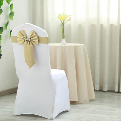 Elegant white chair cover with gold bow in a decorated setting.
