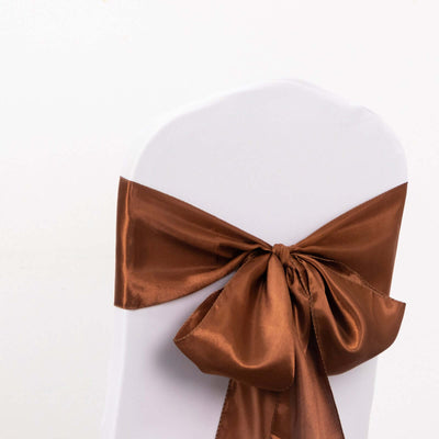 Brown satin chair sash tied in a bow on a white chair.