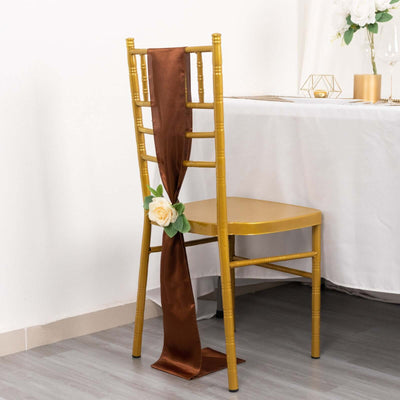 Gold chiavari chair with brown satin sash and flower decoration.