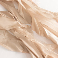Close up of satin and taffeta chair sashes in nude color, styled in a curly willow shape#whtbkgd
