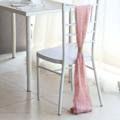 White chair with pink draped fabric at a dining table setting.