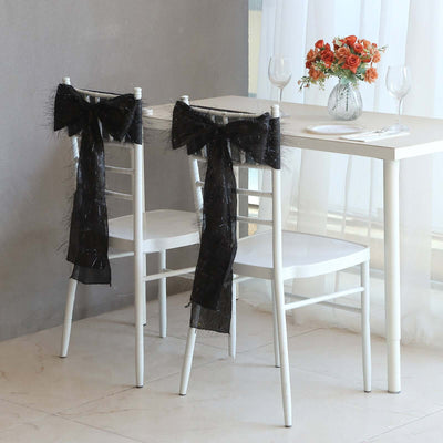 Elegant white chairs adorned with black bows at a dining table.