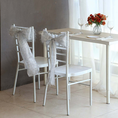 Elegant dining setup with white chairs and a floral centerpiece.