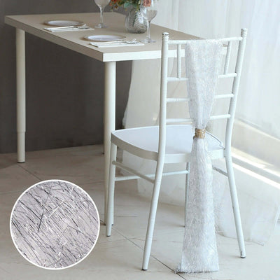 Elegant white chair with decorative fabric drape beside a dining table.
