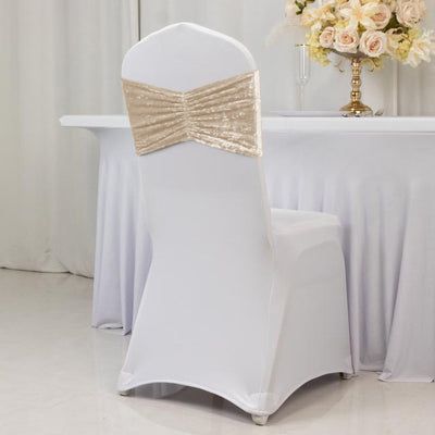 White chair cover with gold sequin bow at a decorated table setting.