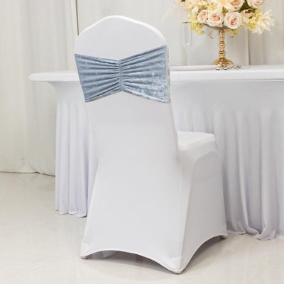 Elegant blue velvet chair cover on a white chair at a dining table.