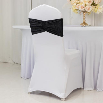 Black chair cover with elegant ruched design on a white chair.