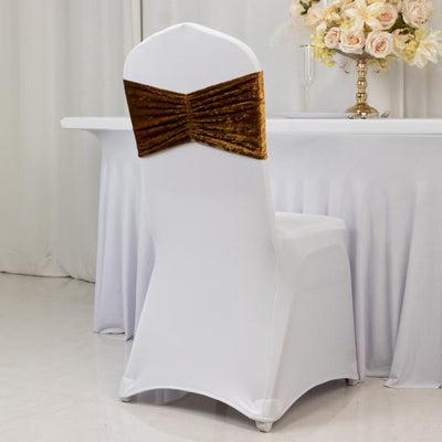 Elegant white chair cover with a gold velvet bow, perfect for event decor.