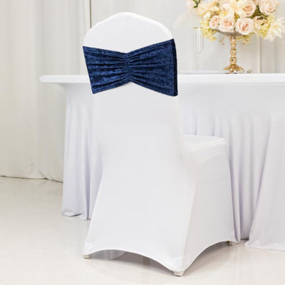 Navy blue chair cover with ruched bow on a white chair at a decorated table.