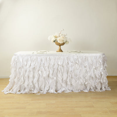 White ruffled table skirt with a floral centerpiece on a table.