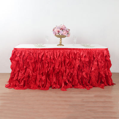 Red ruffled table skirt with floral centerpiece on a table.