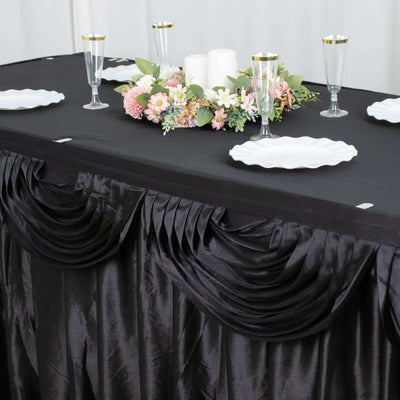 Elegant black tablecloth with pleats, set for dining with floral centerpiece and tableware.