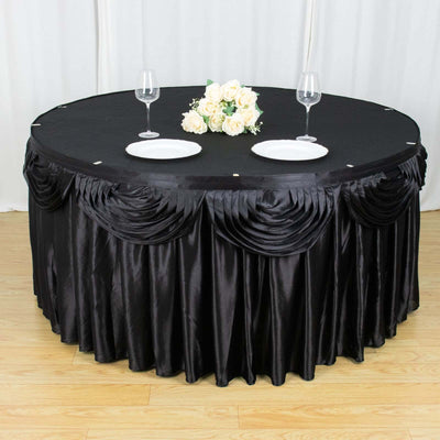 Elegant black tablecloth draped on a round table with plates and flowers.