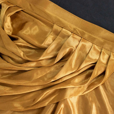 Golden satin fabric with elegant draping and pleats.