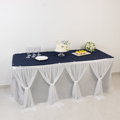 Elegant navy tablecloth with white draping, glassware, and cake display.