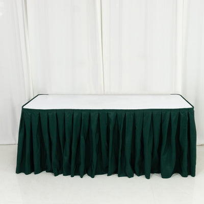 Green table skirt with pleats on a plain white backdrop