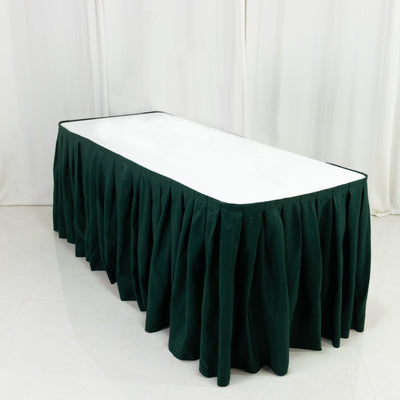 Green table skirt on a white table against a plain backdrop.