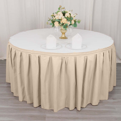 Round table with beige tablecloth and floral centerpiece.