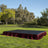 Outdoor event stage with black top and burgundy skirt in a park setting.
