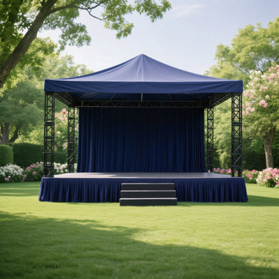 Outdoor event stage with navy blue drapery and steps in a lush garden setting.