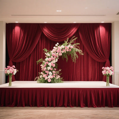 Floral arrangement on stage with red drapery backdrop.