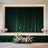 Elegant green velvet stage backdrop with floral arrangements in vases.